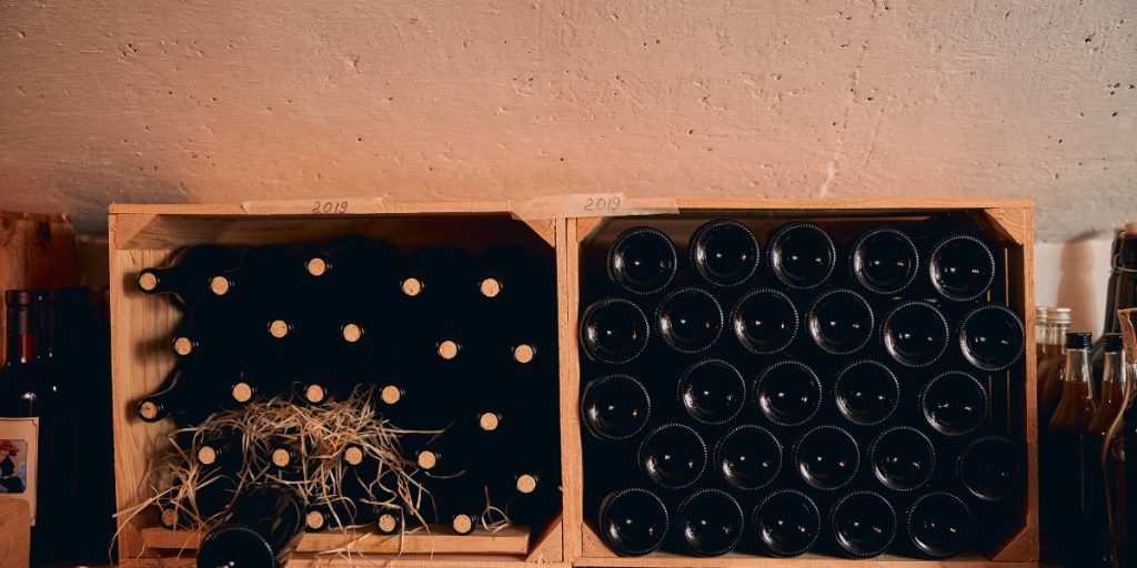 Wine bottles are carefully organized and packed in wooden shipping crates with protective padding, demonstrating proper long-distance wine shipping process packaging and storage methods.