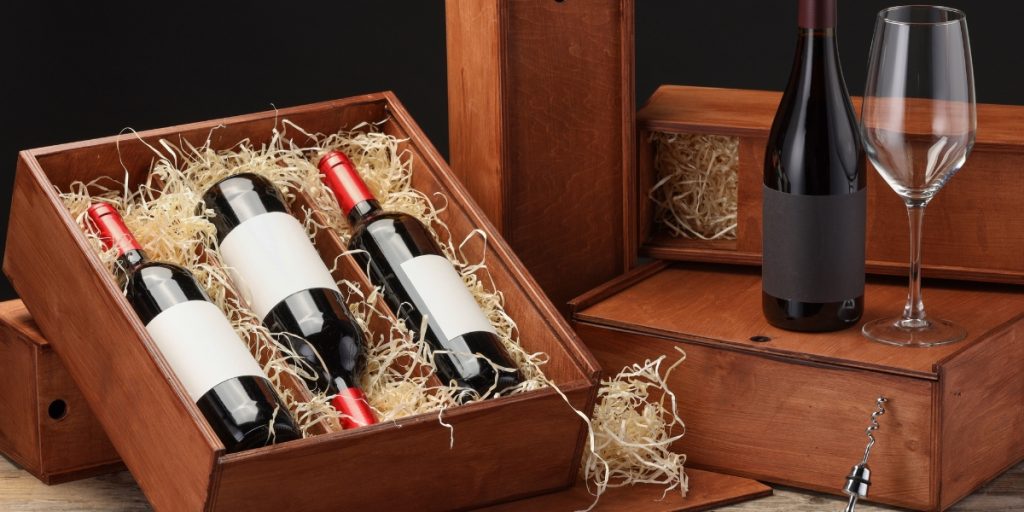 Elegant wooden wine boxes with protective straw padding demonstrating proper packaging for shipping rare wines safely with bottles and wine glass displayed