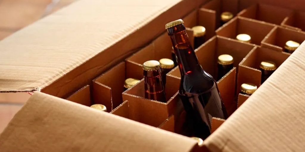 What states allow alcohol delivery close-up view of beer and wine bottles securely packaged in protective cardboard dividers within shipping box ready for delivery compliance.