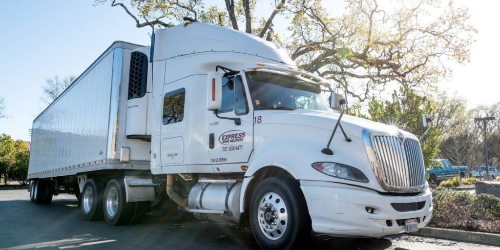 Commercial refrigerated delivery truck with temperature-controlled shipping trailer and express service branding parked in outdoor setting for safe wine transport and climate-controlled logistics