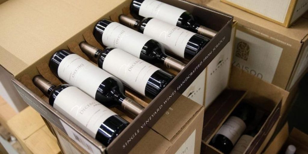 Premium wine bottles carefully packaged in a cardboard box with white protective wrapping and tissue padding, illustrating the protective measures used in how we protect wine bottles during shipping.