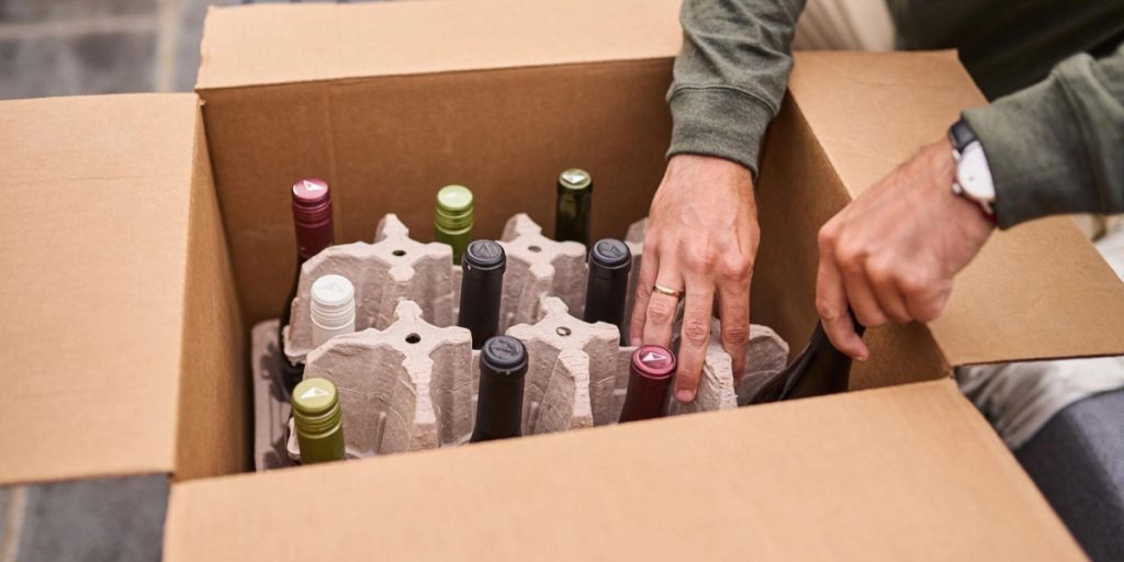 Wine bottles of various colors secured in cardboard egg carton-style inserts within a wine shipping box, showcasing how wine shipping boxes provide individual compartments and cushioning for safe wine transport.