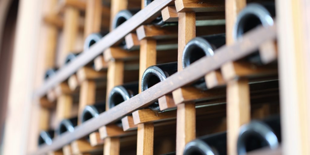 Wine club logistics featuring organized wine bottle storage with metallic rings and wooden support structures in a professional cellar or wine rack system.