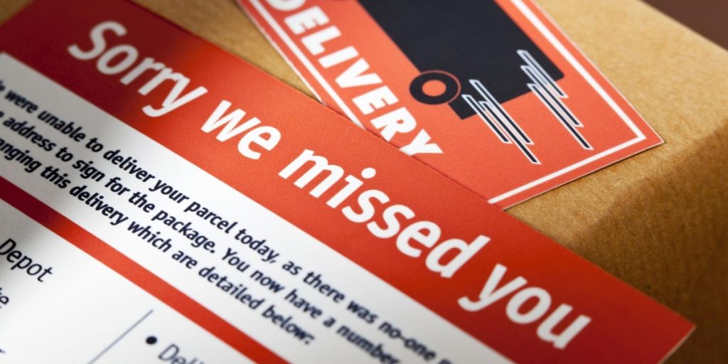 A “Sorry we missed you” delivery slip rests on a cardboard package, a common sight after a missed wine delivery.